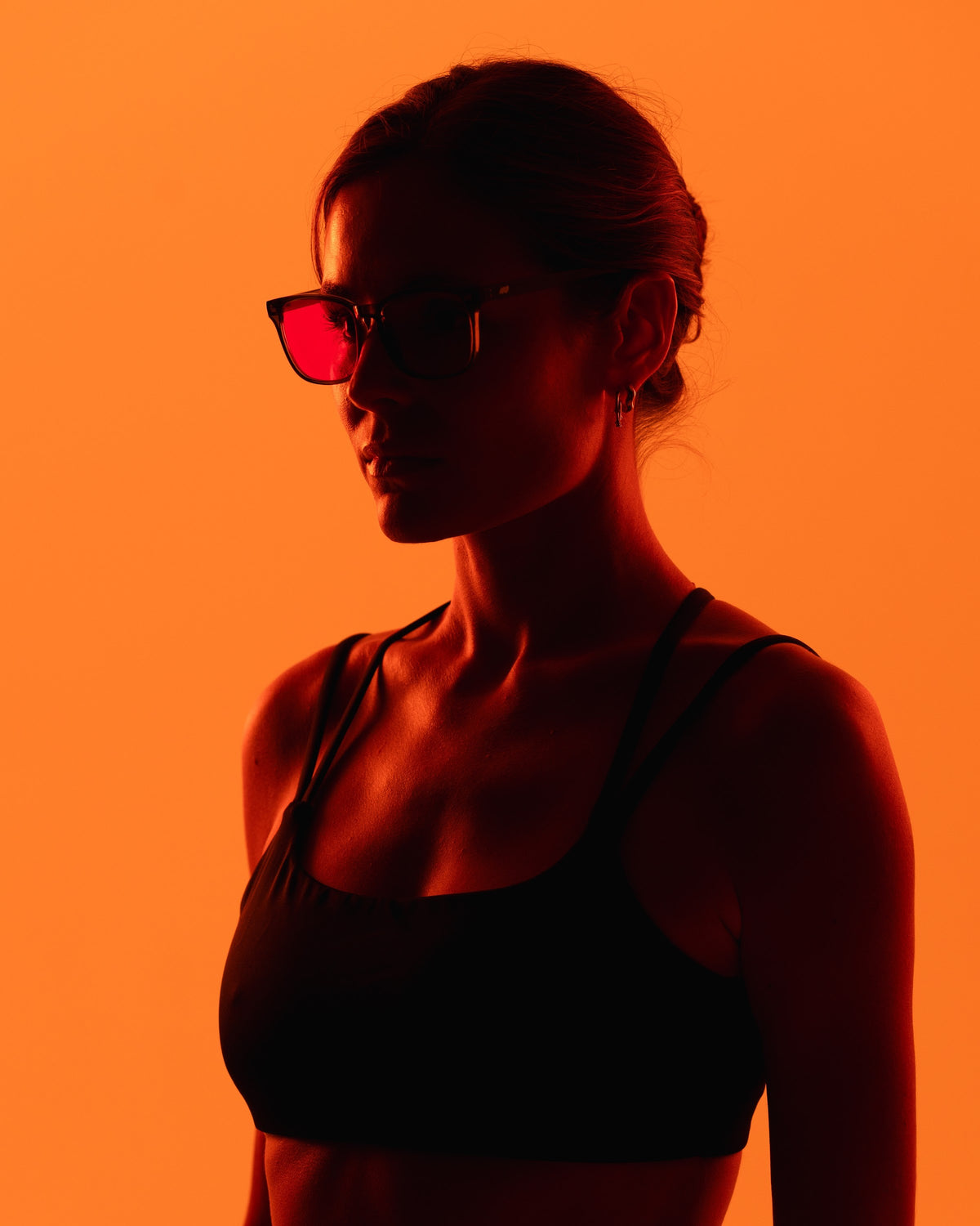 Woman wearing 8Hours blue blocking glasses against an orange background