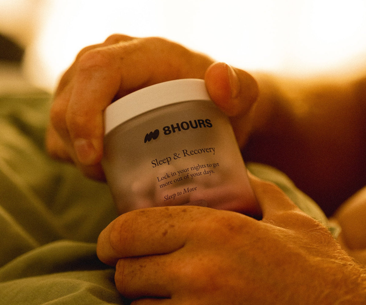 Ben White holding a jar of 8HOURS Sleep & Recovery in bed