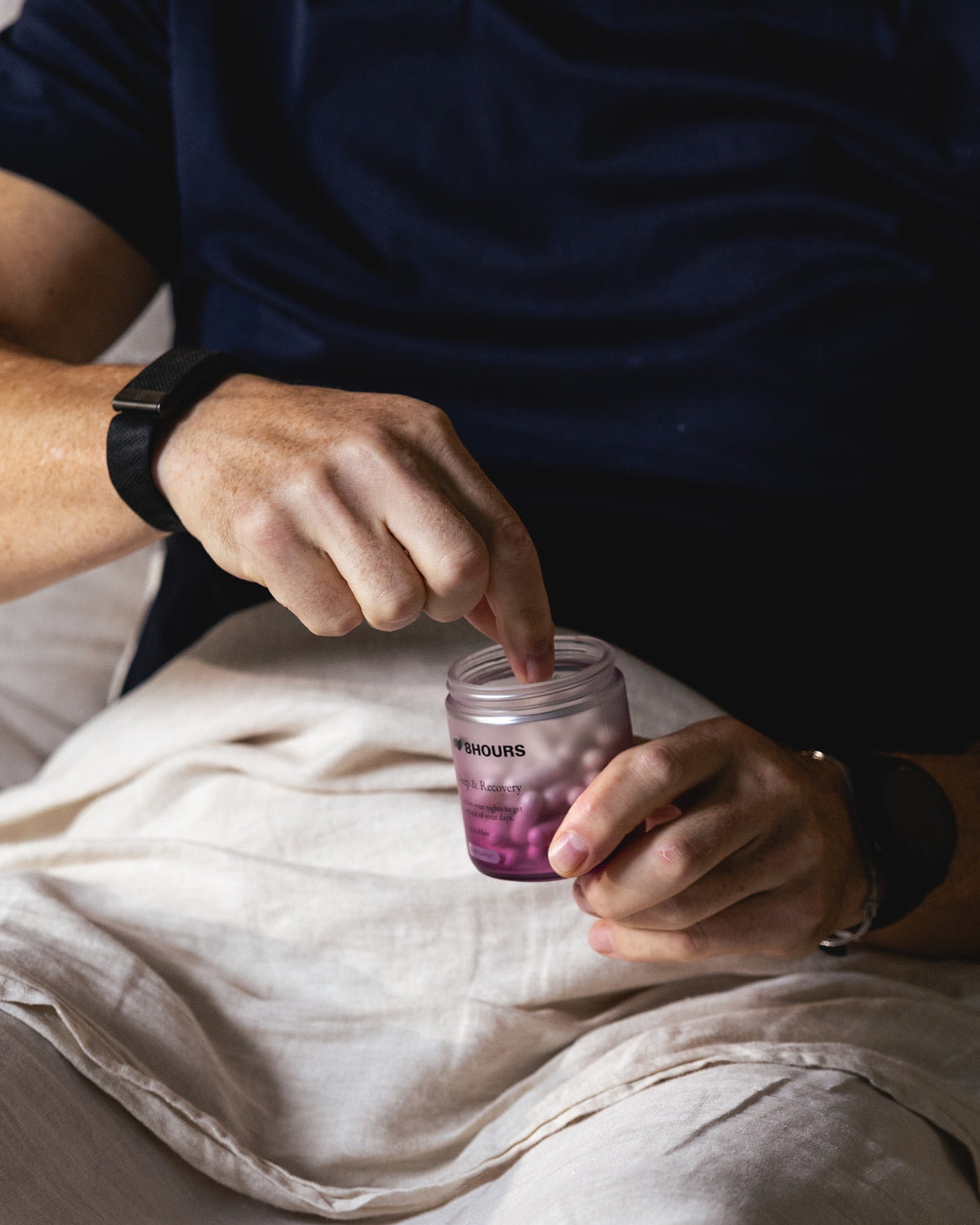 Taking two Sleep & Recovery capsules from the jar in bed