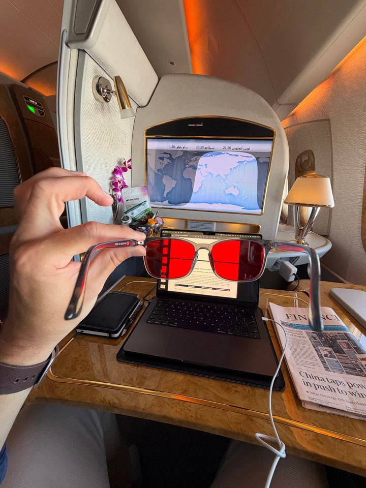 Customer photo: holding 8HOURS blue blocking glasses in a first-class airline suite