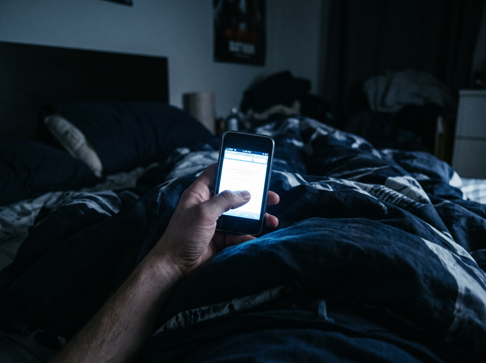 An early smartphone glowing in bed at night