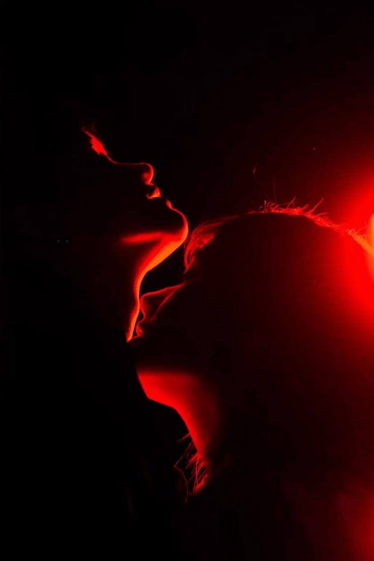 Two faces close together in red light