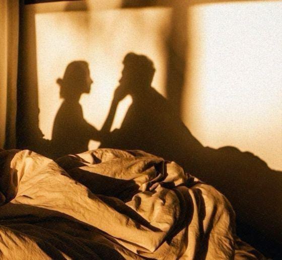 Shadows of a couple on a bedroom wall in warm light