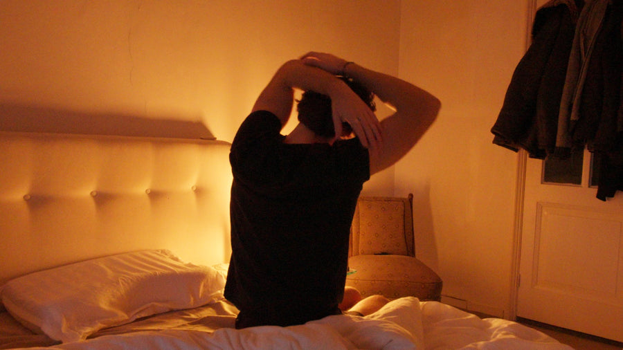 Person sitting on the edge of a bed in warm light